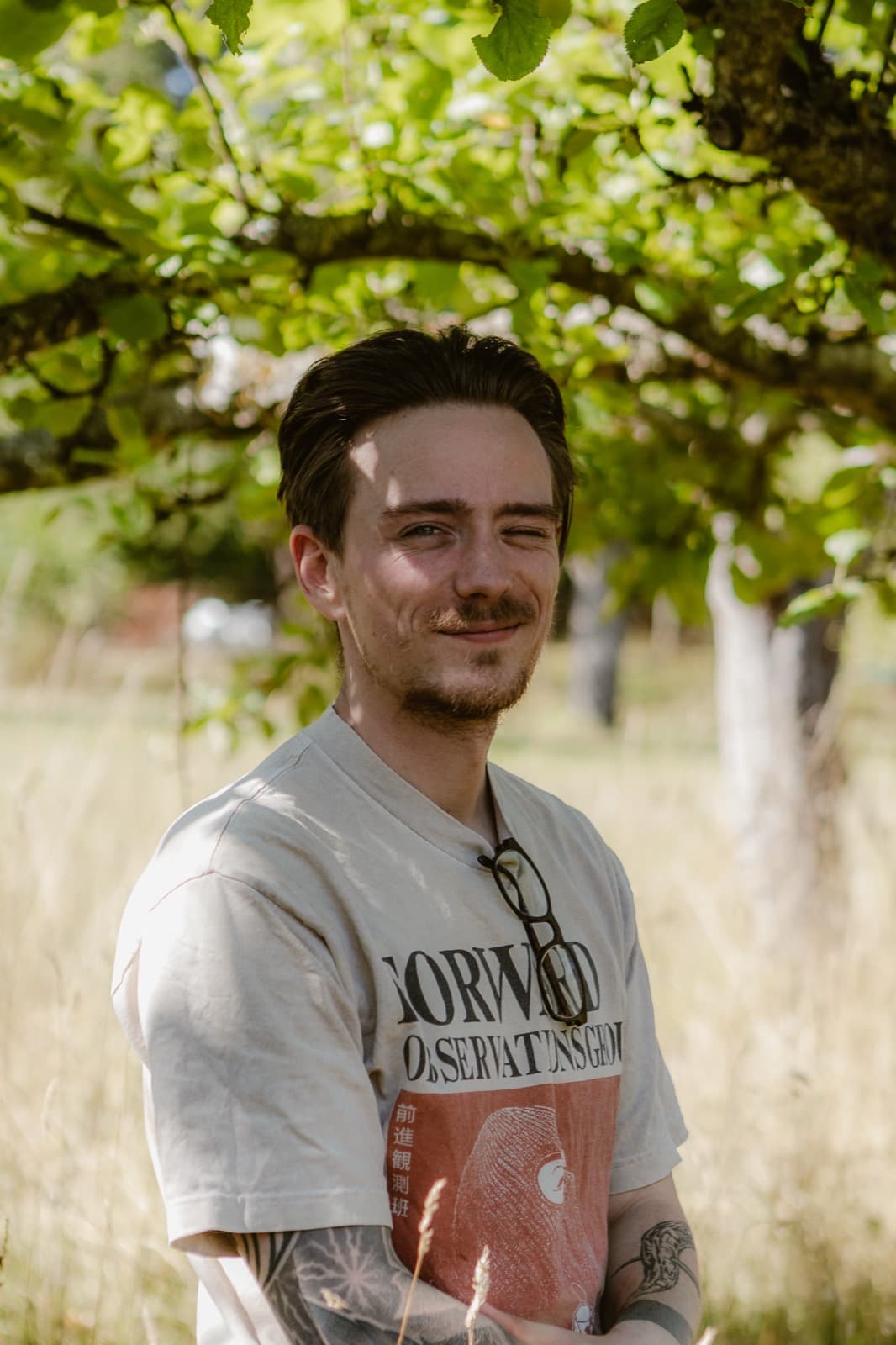 Samuel Schäck zwinkernd vor einem Obstbaum
