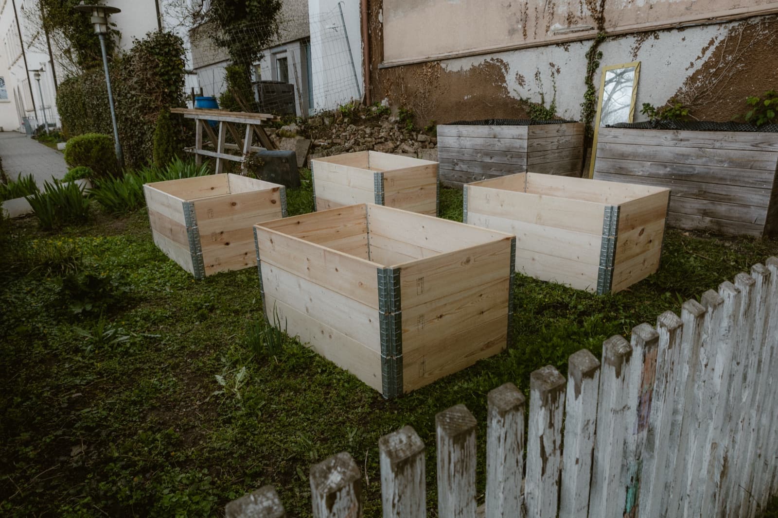 Frisch aufgebaute Hochbeete neben den alten, verwitterten Beeten im Schulgarten