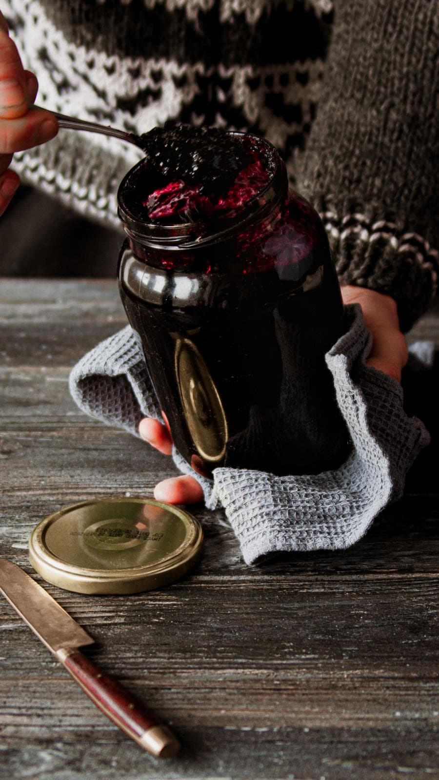 Dunkelrote Holunderbeeren-Marmelade wird in ein Glas gefüllt